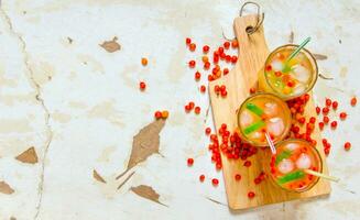 Three cocktails from sea-buckthorn berries , ice and lime on the old table . Free space for text. photo