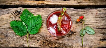 Cocktail of wild strawberries with ice on a wooden table. photo