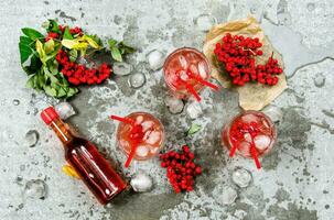 Three cocktails with ice.  Ingredients - liquor, berries, juice, and clean water on the stone table. photo