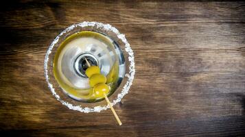 Martini with olives on a wooden table. Free space for text. photo