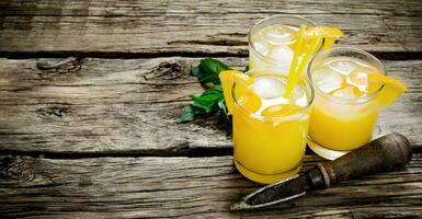 Cocktail of fresh oranges with ice and straw on wooden background . Free space for text. photo