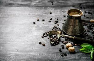 Coffee pot with coffee beans, cane sugar and fresh leaves. photo