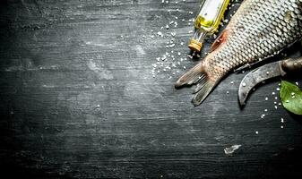 Fish with an old carving knife and olive oil. photo