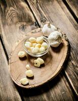 Peeled cloves of garlic on a wooden trunk. photo