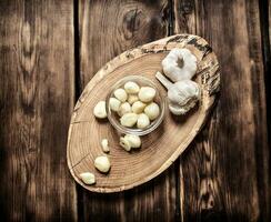 Peeled cloves of garlic on a wooden trunk. photo