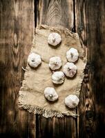 Garlic on a old sack. On wooden background. photo
