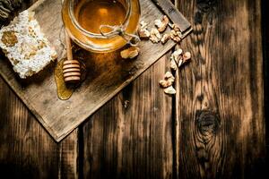 dulce miel en el peine, vaso tarro con nueces. foto