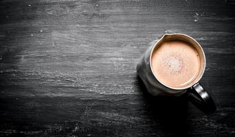 pitcher of hot chocolate. On black rustic background. photo