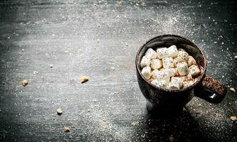 Hot chocolate with marshmallows. On black chalkboard. photo