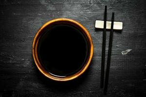 Soy sauce in a bowl and chopsticks. photo