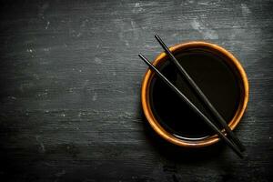 Soy sauce in a bowl and chopsticks. photo