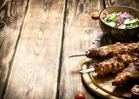 Kebab with fresh salad of cucumbers and onions. photo