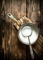 Sour cream in the pan with a ladle. photo