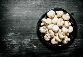 Fresh mushrooms on the plate. On black rustic background. photo