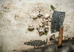 Sliced mushrooms with spices and a large hatchet. photo