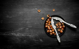 Hazelnuts with Nutcracker on the old plate. photo