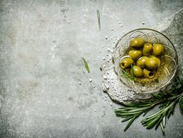 Olives with rosemary on a stone stand. photo