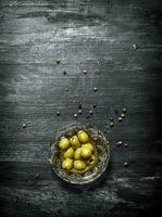 Olives in oil with spices. On black rustic background. photo