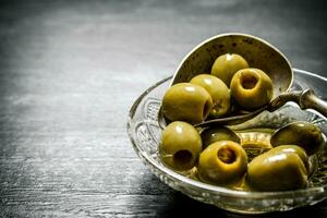 Olives in olive oil with an old spoon. photo