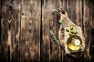 aceituna petróleo con Romero rama. en de madera antecedentes. foto