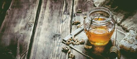 dulce miel en el peine, vaso tarro con nueces. foto