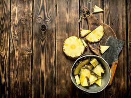 Slices of pineapple in a pot with an axe. photo