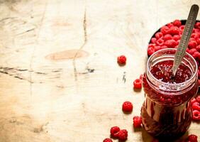 Sweet raspberry jam in jar with spoon. photo