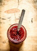 Sweet raspberry jam in jar with spoon. photo