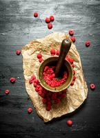 Red raspberries in a mortar with pestle. photo