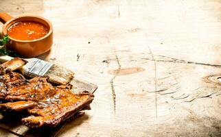 Smoked pork ribs with hot sauce and a brush. photo