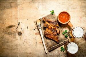 Smoked barbecue ribs with tomato sauce and cold beer. photo