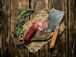 Sliced salami with a hatchet and rosemary. photo