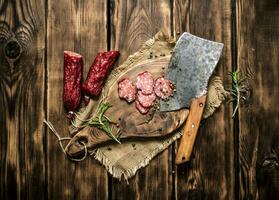 rebanado salami con un hacha y Romero. foto