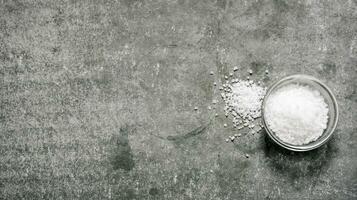 Salt in the Cup. On stone background. photo