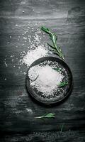 Coarse salt in the pan and branches of rosemary. photo