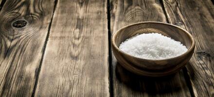 Wooden Cup with salt . On wooden background. photo