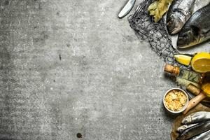 Fresh fish with lemon and spices on a fishing net. photo