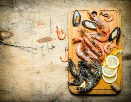 Fresh seafood. Cutting Board with shrimp, shellfish and lemon. photo