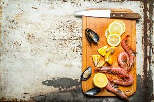 Fresh seafood. Cutting Board with shrimp, shellfish and lemon. photo