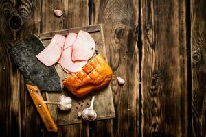 Ham with a hatchet and garlic on the Board. photo