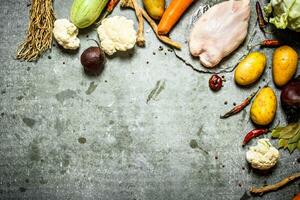 Raw chicken with the ingredients for soup. photo