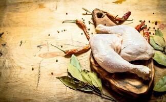 Raw chicken with peppercorn and bay leaves on the Board. photo