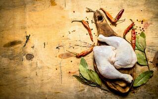 Raw chicken with peppercorn and bay leaves on the Board. photo