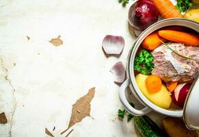 Soup with vegetables, pork, spices and herbs in a saucepan. photo