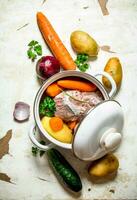 Soup with vegetables, pork, spices and herbs in a saucepan. photo