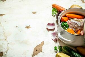 Soup with vegetables, pork, spices and herbs in a saucepan. photo