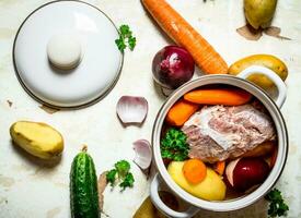 Soup with vegetables, pork, spices and herbs in a saucepan. photo