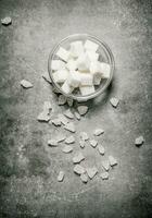 Refined sugar in a glass saucer. On stone background. photo