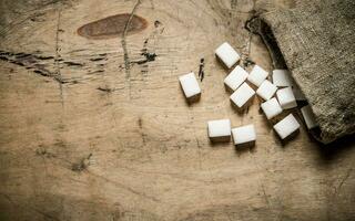 blanco refinado azúcar en el bolsa. en de madera antecedentes. foto