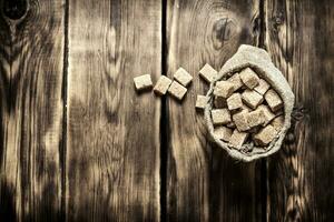Cane sugar refined in the bag. On wooden background. photo